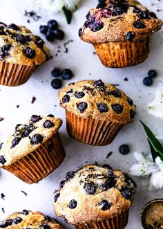 blueberry muffins on a white surface with flowers