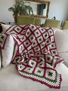 a crocheted blanket is sitting on a couch next to a pillow and mirror