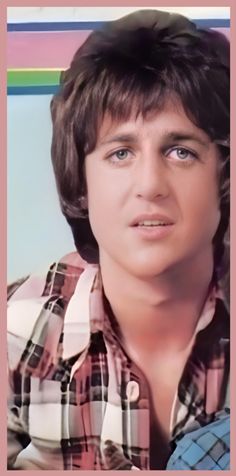 an old photo of a young man with short hair and plaid shirt looking at the camera