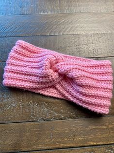 a pink knitted headband laying on top of a wooden floor