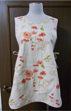 a white dress with red flowers is hanging on a wooden door handle and it's made out of fabric