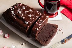 a slice of chocolate cake on a plate next to a mug and peppermint