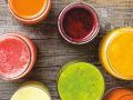 six cups filled with different colored liquids on top of a wooden table next to each other