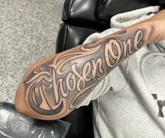 a man with a tattoo on his arm that says chosen one in cursive writing