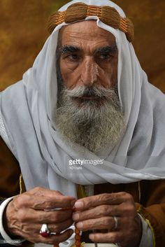 an old man wearing a white turban and holding a rosary in his hands