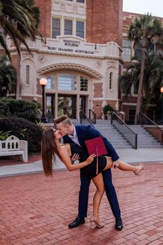 a man and woman kissing in front of a building with palm trees on the sidewalk