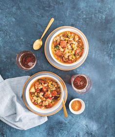 two bowls filled with food sitting on top of a blue table next to spoons