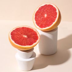 two grapefruits sitting on top of each other in front of a cup