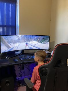 a young boy sitting in front of a computer monitor on top of a black desk