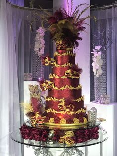 a red and gold wedding cake sitting on top of a glass table