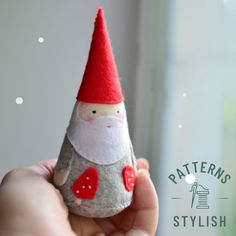 a hand holding a small rock with a gnome on it's face and a red hat