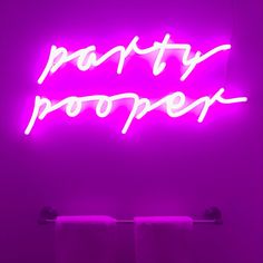 a neon sign that says party proof in white letters on a purple wall behind two towels