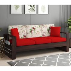 a red and white couch sitting in a living room next to a potted plant