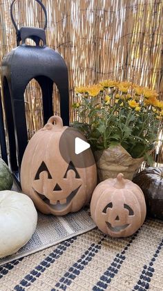 three pumpkins sitting on top of a table next to a lantern and some flowers