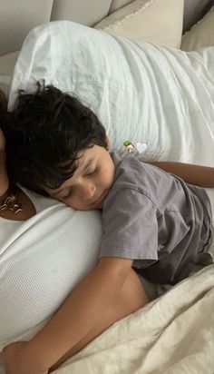 a man and child laying in bed with the boy sleeping on top of his back