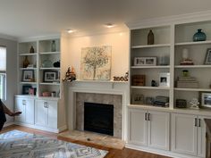 a living room filled with lots of white furniture and bookshelves next to a fire place