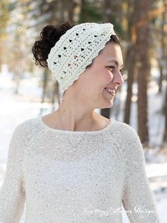 a woman wearing a white crochet headband in the snow with trees behind her