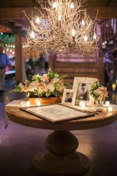 an arrangement of flowers and candles on a table in front of a chandelier