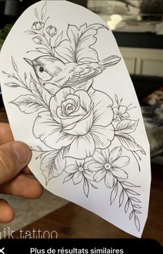 a person holding up a piece of paper with flowers and birds on it in their hand