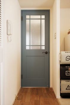 a blue door in a white room with hard wood flooring