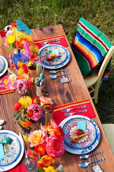 the table is set with colorful flowers and plates