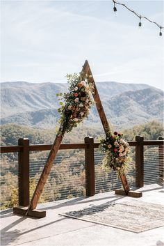 an outdoor ceremony setup with flowers and greenery on the top of a wooden structure