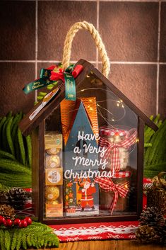 a small house with christmas decorations and lights on the front, sitting next to pine cones