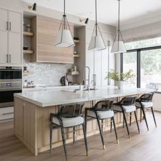 a large kitchen with an island and lots of chairs around the counter top, in front of windows