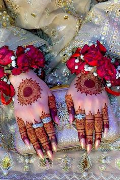 two hands with henna tattoos and flowers on them