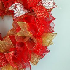 a red and gold mesh wreath on a white wall