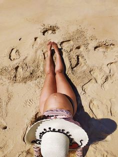 a woman laying on top of a sandy beach