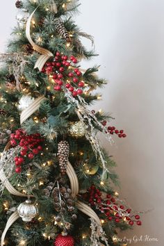 a decorated christmas tree with red berries and pine cones