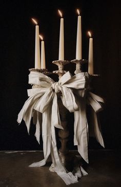 a group of candles that are sitting on top of a wooden stand with ribbon wrapped around them