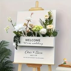 an easel with flowers on it and a welcome sign