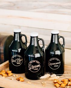 three black jugs sitting on top of a wooden tray filled with nuts and peanuts