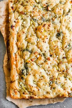 a square casserole with broccoli and cheese on top, sitting on parchment paper