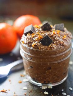 a close up of a dessert in a jar on a table next to oranges