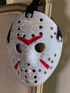 a mask hanging from the back of a chair with sequins and beads on it