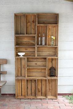 a wooden shelf sitting on top of a brick floor next to a white wall and stairs