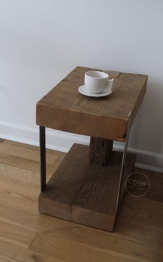 a small wooden table with a white cup on it and a metal frame around the edge