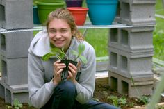 a woman kneeling down holding a plant in her hands