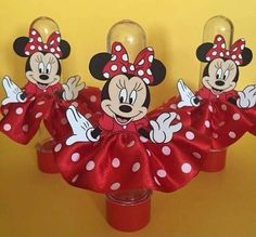 three mickey and minnie mouse wine glasses with red bows on the top, sitting in front of a yellow background