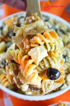 a spoon filled with pasta salad on top of an orange and white checkered table cloth