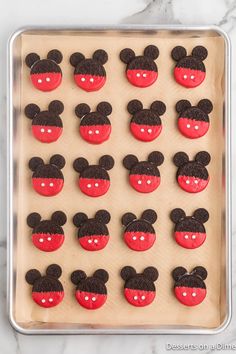 mickey mouse cupcakes on a cookie sheet with red and black frosting in the shape of ears