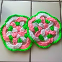 two crocheted coasters sitting on top of a tiled floor