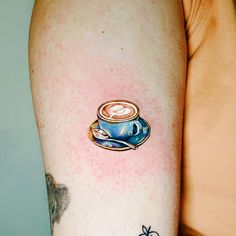 a person with a tattoo on their arm has a coffee cup in the middle of his arm