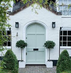 a white brick house with two potted plants in front of the door and windows