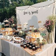 a table topped with cakes and cupcakes under a sign that says love is sweet