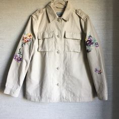 A Floral Embroidered Jacket Is The Next Addition To Your Outerwear Collection With Multiple Pockets And Front Button Closure. - Point Collar - Front Button Closure - Long Sleeves With Floral Embroidery Details - 2 Front Chest Flap Pockets - 2 Side Pockets - Solid - Approx. 28" Length 100% Cotton Machine Wash Cold Nwot Floral Embroidery Long Sleeve Workwear Outerwear, Floral Embroidered Long Sleeve Workwear Outerwear, Floral Embroidery Long Sleeve Outerwear For Work, Fall Beige Outerwear With Floral Embroidery, Beige Floral Embroidered Outerwear For Fall, Collared Cotton Outerwear With Embroidery, Collared Embroidered Cotton Outerwear, Embroidered Cotton Collared Outerwear, Embroidered Cotton Outerwear For Work