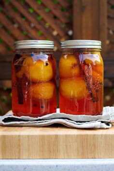 two jars filled with fruit sitting on top of a wooden table